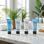 H2O Therapy hotel amenities: shampoo, conditioner, body lotion, body wash on marble counter with plants